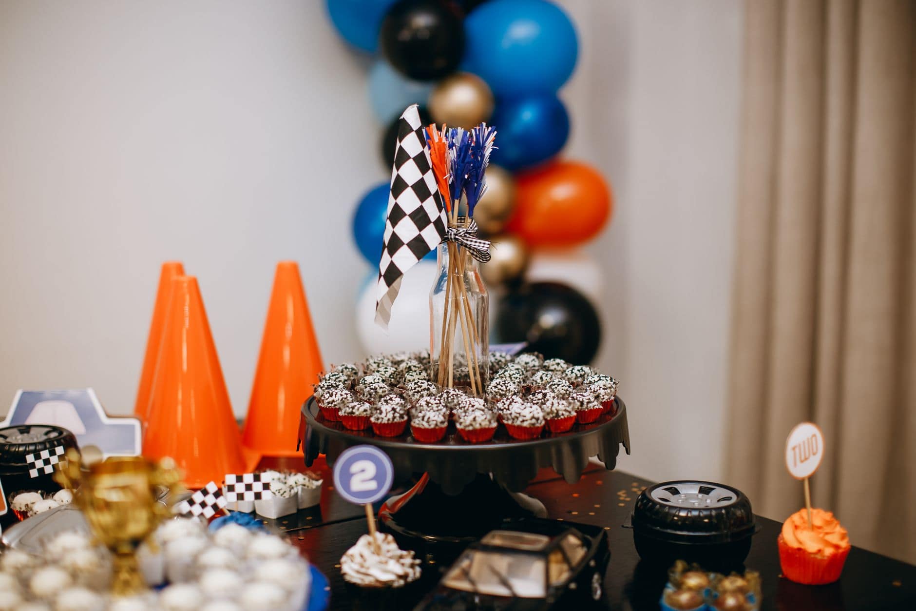 Racing themed party table with cupcakes, balloons, and checkered flags creating a festive atmosphere.