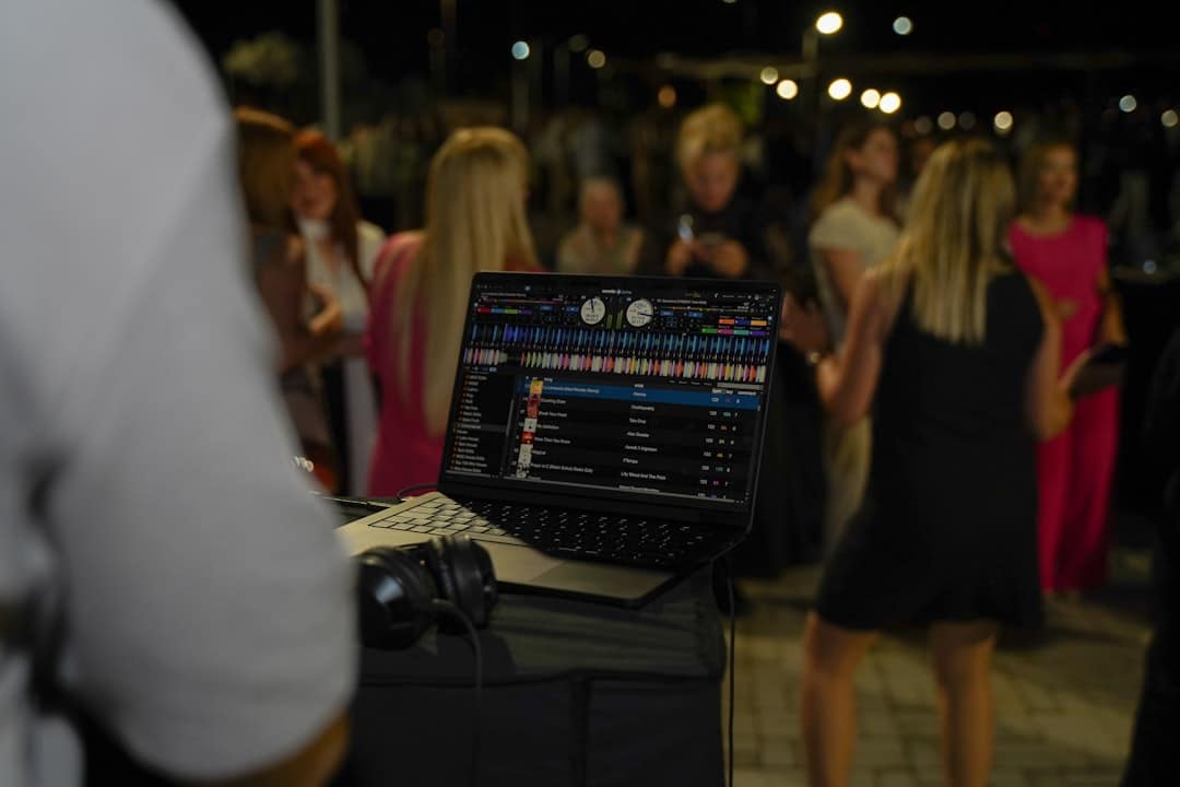 Dj mixing music on a laptop at a night party.